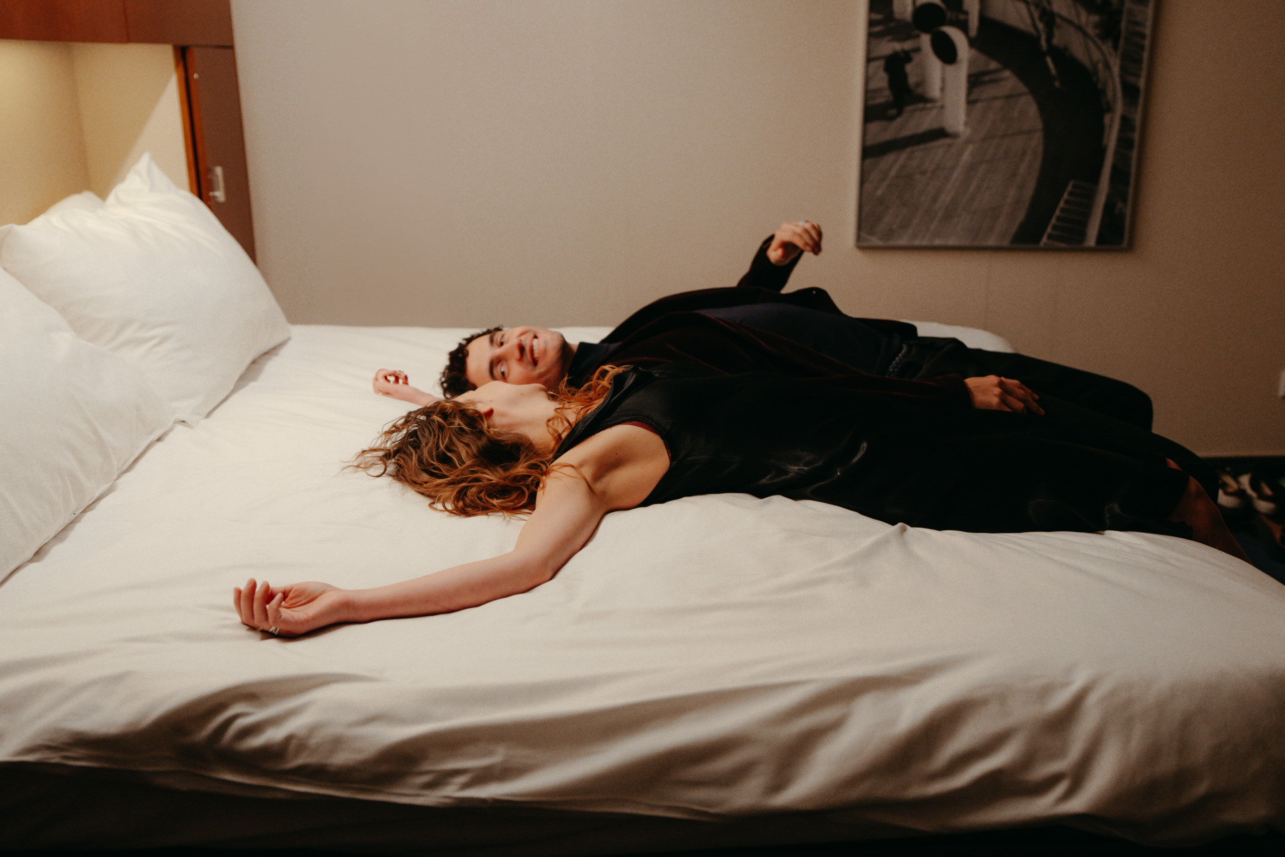 Een man en een vrouw liggen samen op de dekens van het bed in de hotelkamer